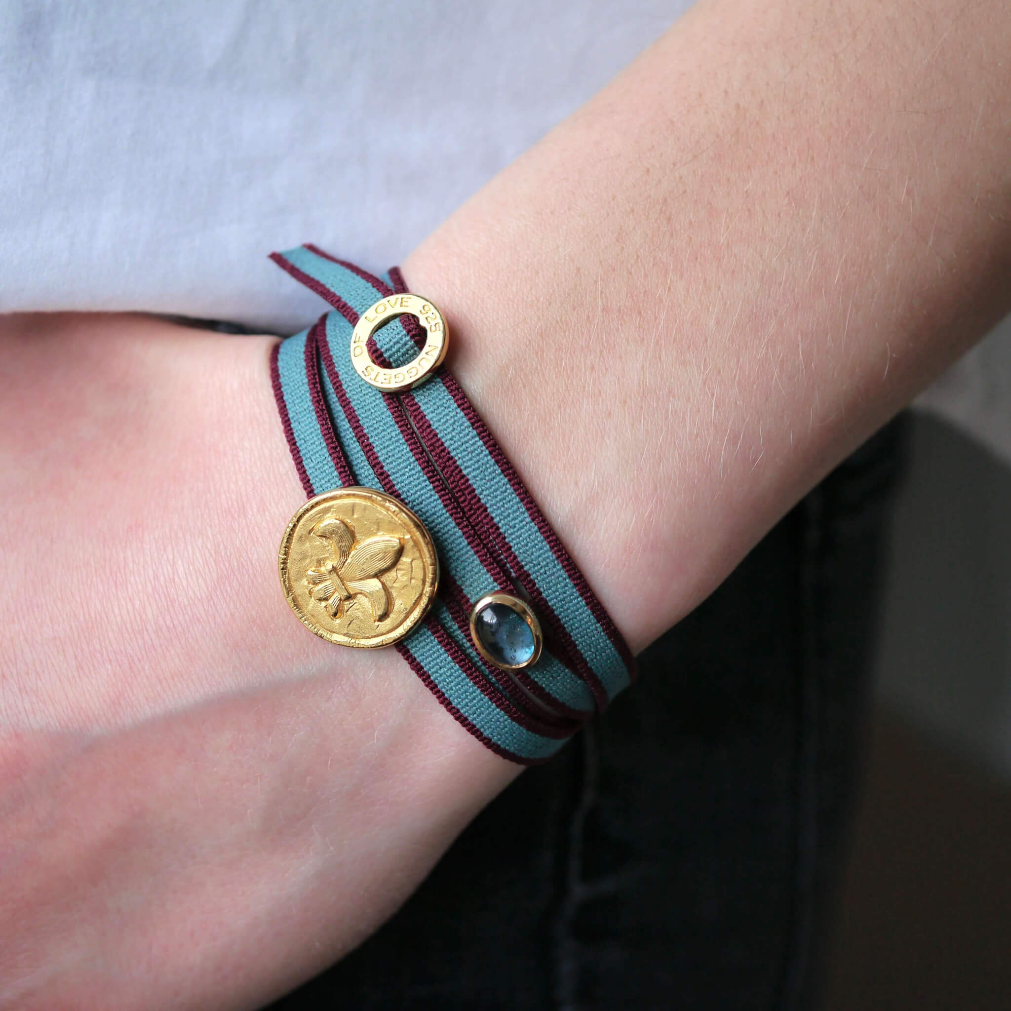 gestreiftes Wickel bzw. Sammelarmband in jeansblau-bordo mit vergoldeter Fleur de Lis und Blautopas. Exklusives, dehnbares Armband von True Nuggets