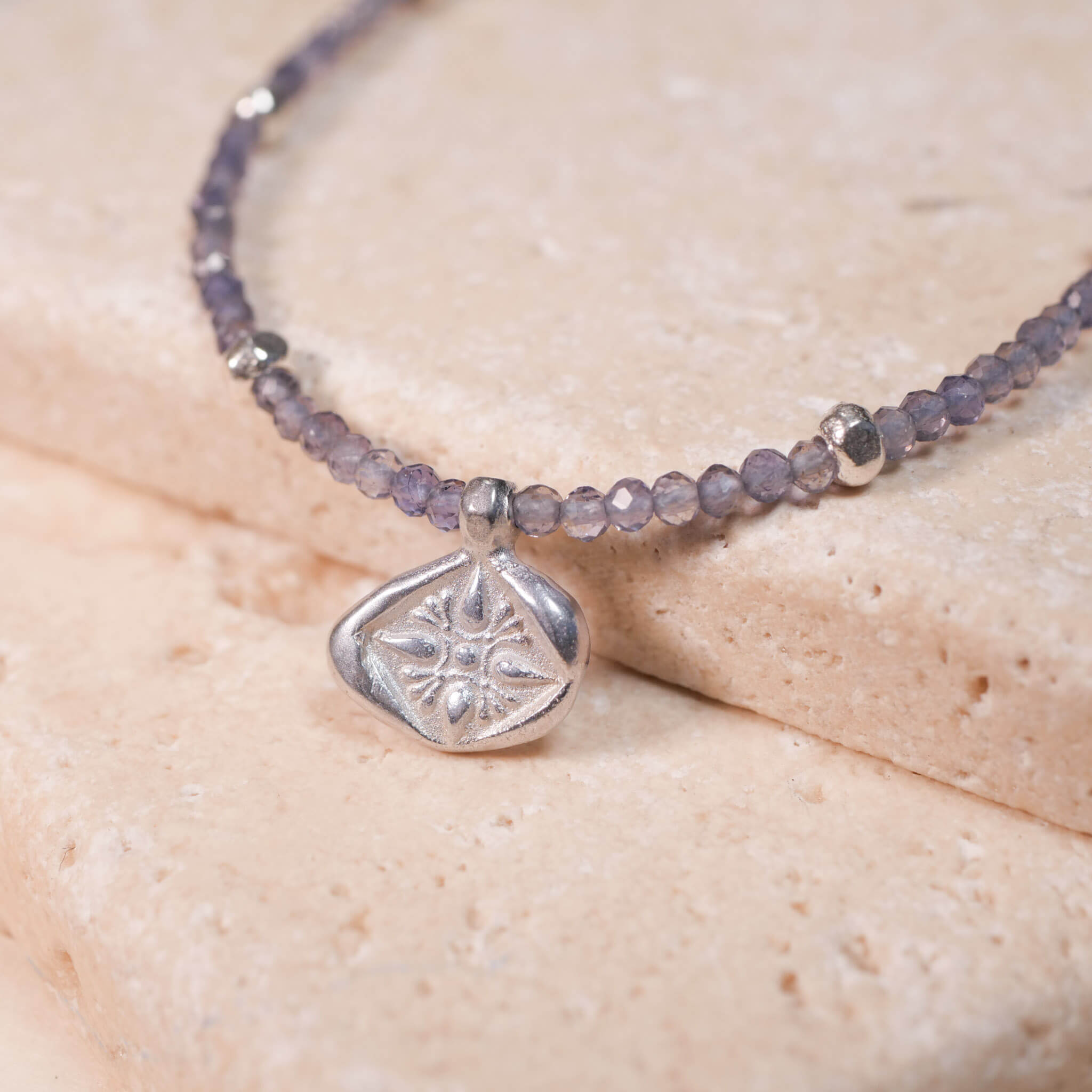 Kette mit der Münze Leona aus rauchblauen iolith Edelsteinen. Der Münzanhänger hat zwei Seiten ein mit Stern und ein mit Löwen. Hier ist das Sternenmotiv zu sehen. aus Sterling Silber. True Nuggets