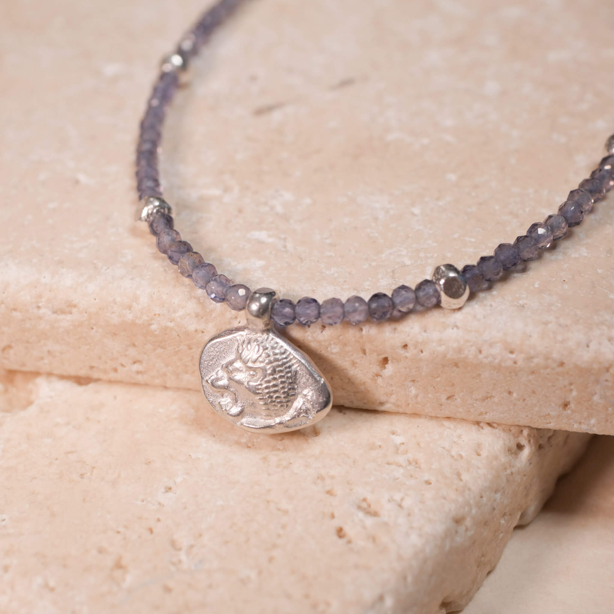 Kette mit der Münze Leona aus rauchblauen iolith Edelsteinen. Der Münzanhänger hat zwei Seiten. Hier ist der Löwenkopf zu sehen. aus Sterling Silber. True Nuggets. Diese Münze ist eine Nachprägung einer antiken griechischen Münze um ca. 511 v. Chr.