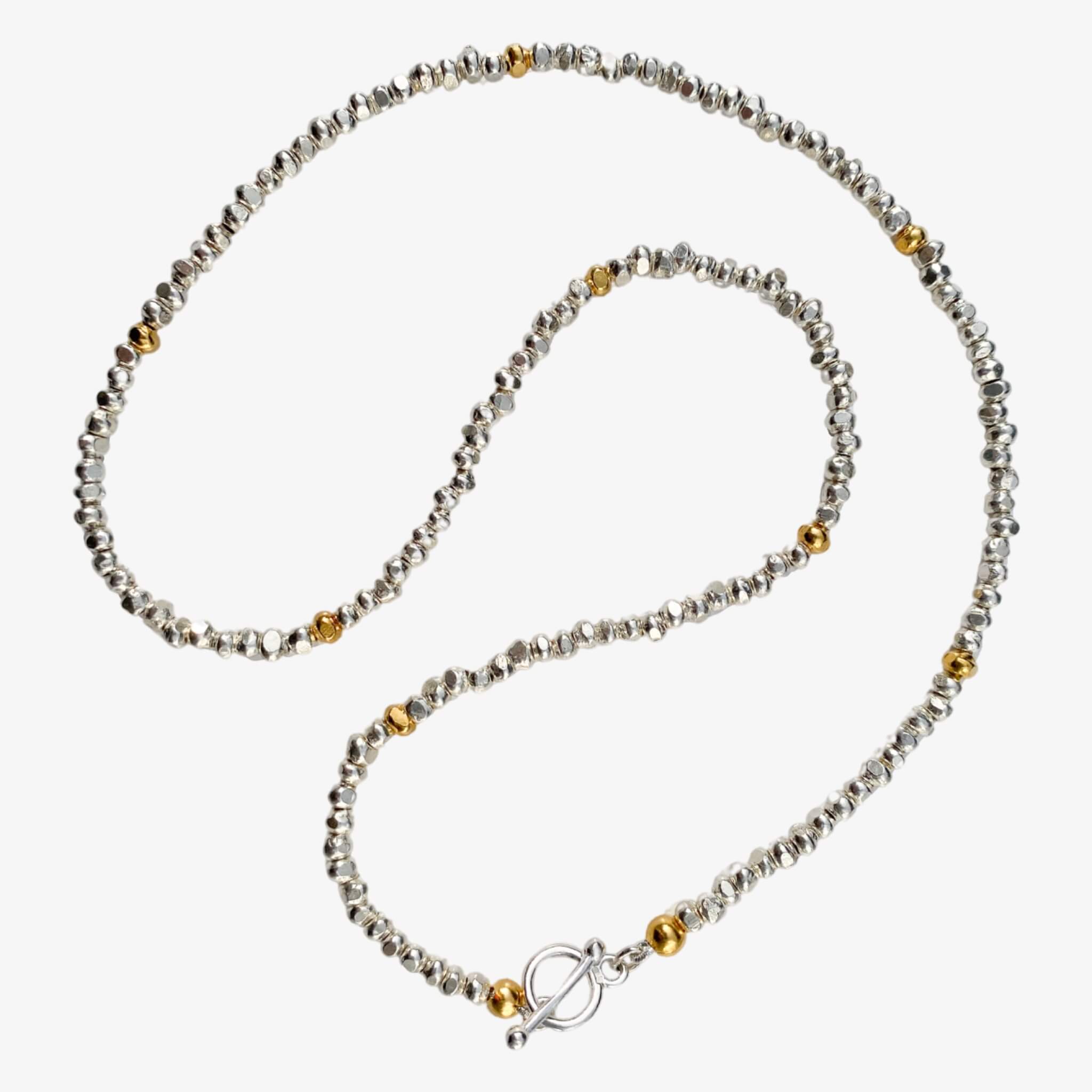kette aus handgeschmiedeten Nuggets - Silberperlen aus 925er Sterling Silber. Einzeln eingestreut sind vergoldete Nuggets, die die Kette noch besonderer machen und zu all deinen anderen Schmuckstücken kombinierbar macht. Von True Nuggets